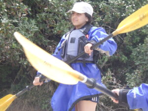 Lili in spray skirt, holding kayak paddle